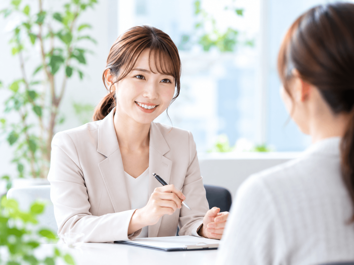 明るい相談室で女性相談員が相談者の話を丁寧に聞く様子